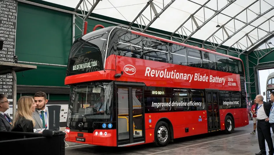 Red BYD BD11 double-decker bus displayed at a London launch event.