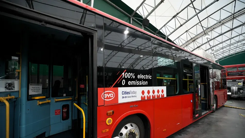 Side view of the BYD BD11 electric bus inside a London transport venue.