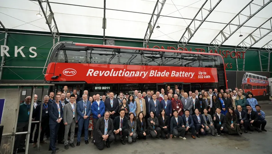 Launch group assembled in front of the red double-decker bus.