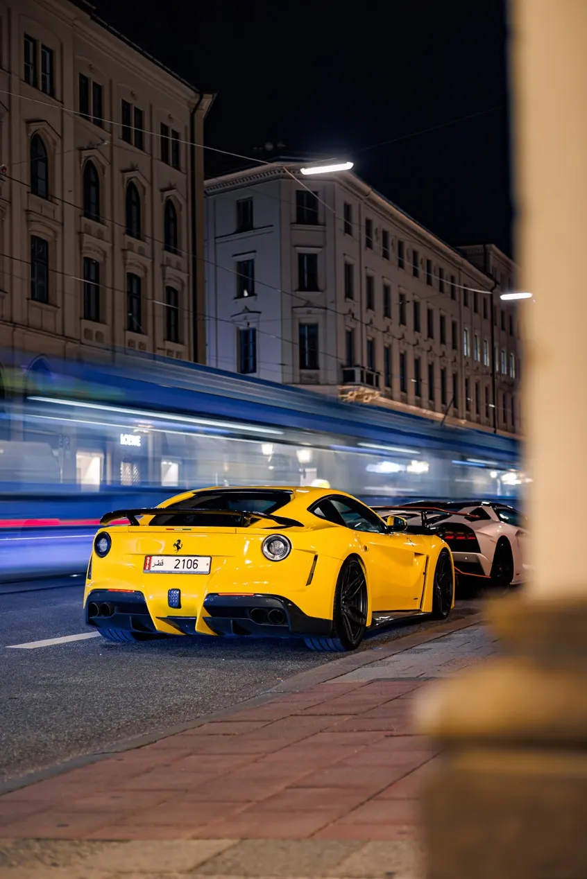 Yellow sports car moving through a city street at night.